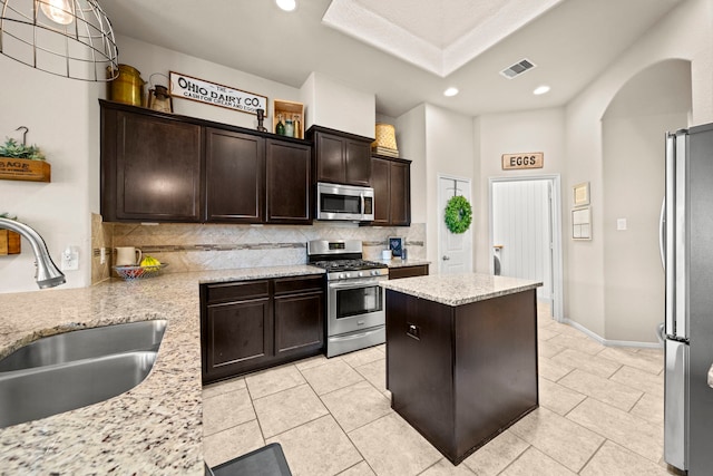 kitchen featuring a sink, stainless steel appliances, backsplash, visible vents, and a kitchen island