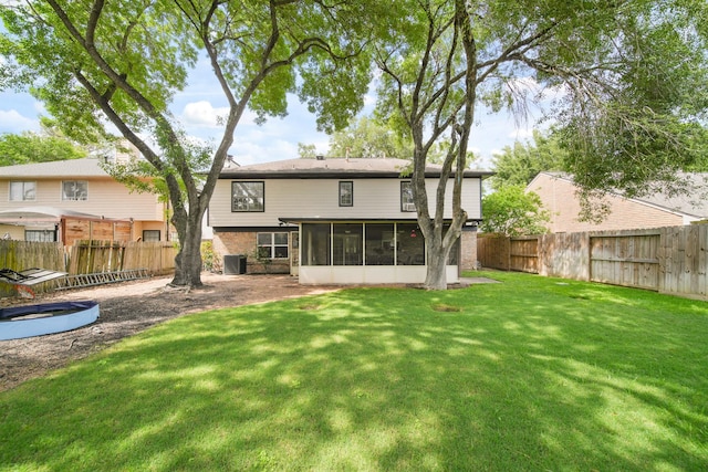 rear view of property featuring a sunroom, a fenced backyard, a lawn, and central AC
