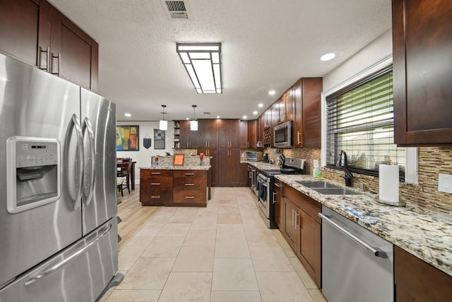 kitchen with visible vents, a kitchen island, tasteful backsplash, a sink, and stainless steel appliances