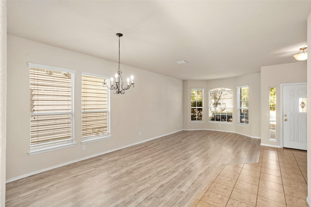 interior space with baseboards, a chandelier, and light wood finished floors
