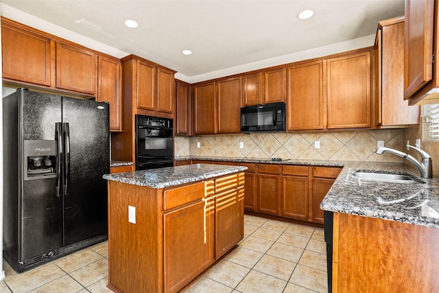kitchen featuring light tile patterned flooring, a kitchen island, dark stone counters, a sink, and black appliances