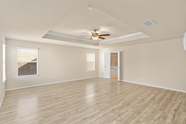 unfurnished room featuring visible vents, a raised ceiling, ceiling fan, and light wood finished floors