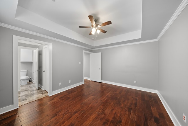 unfurnished bedroom with baseboards, ornamental molding, a raised ceiling, and hardwood / wood-style floors