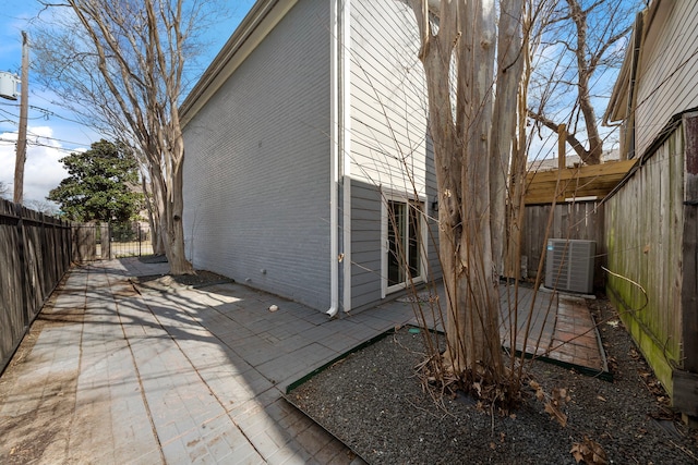 back of property featuring central air condition unit, brick siding, a fenced backyard, and a patio area