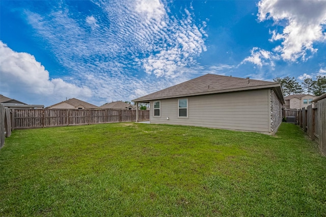 rear view of property with a lawn and a fenced backyard