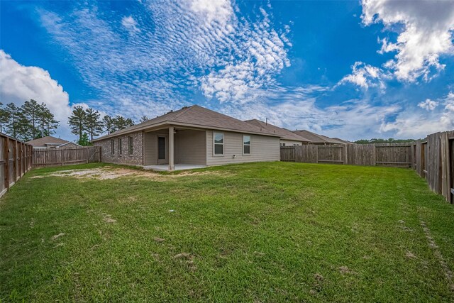rear view of property with a patio, a fenced backyard, and a lawn