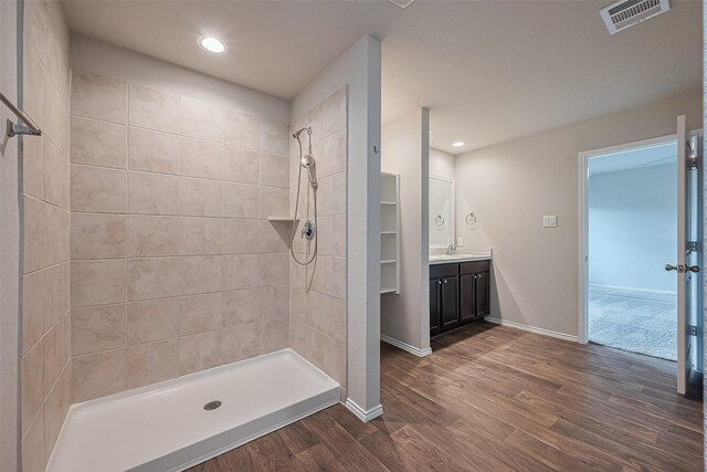 bathroom with visible vents, a tile shower, wood finished floors, vanity, and recessed lighting