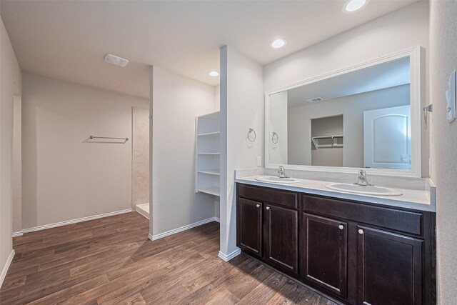 full bathroom with a sink, double vanity, wood finished floors, and visible vents