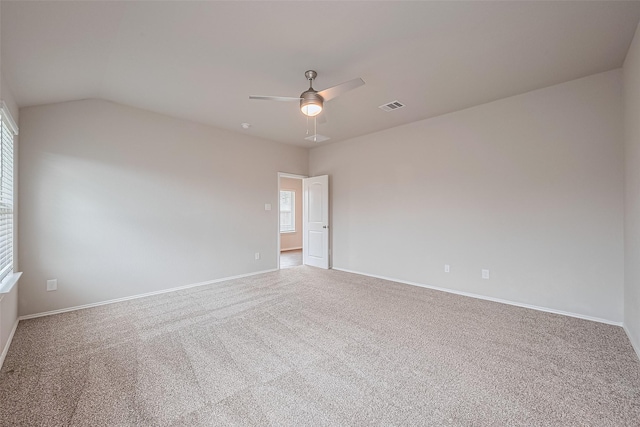 carpeted empty room featuring visible vents, a ceiling fan, baseboards, and vaulted ceiling