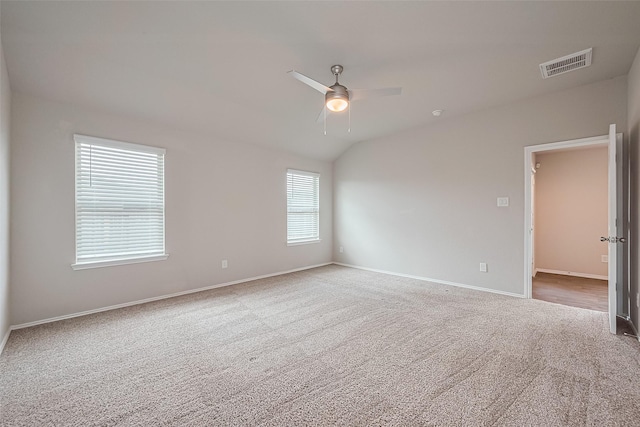 carpeted empty room featuring a ceiling fan, baseboards, visible vents, and vaulted ceiling