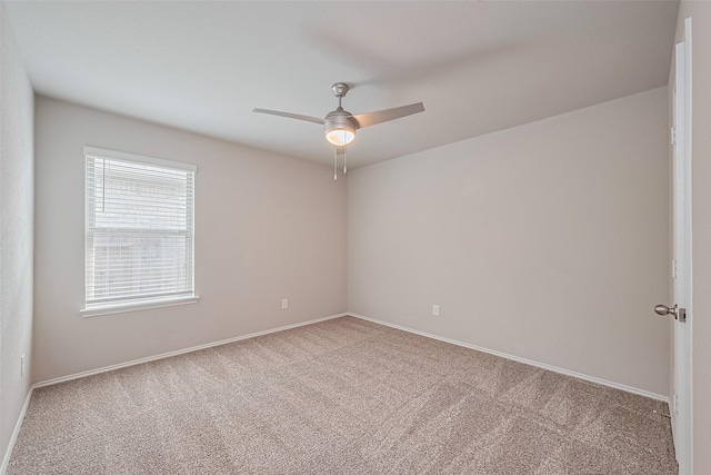 empty room with carpet floors, a ceiling fan, and baseboards