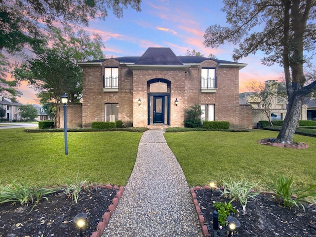 traditional-style home featuring brick siding and a front lawn