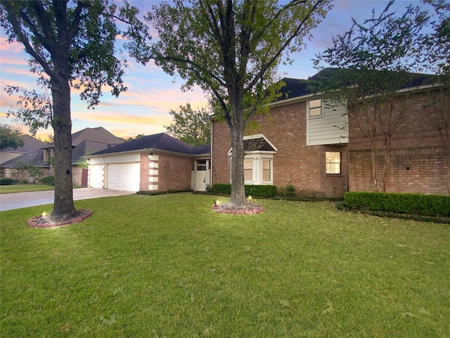 traditional-style house featuring brick siding, an attached garage, driveway, and a front yard