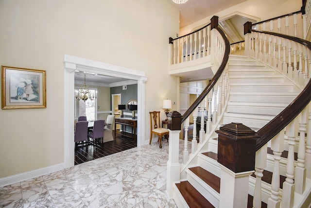 entrance foyer with marble finish floor, stairs, baseboards, a high ceiling, and a chandelier