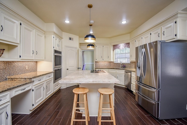 kitchen featuring visible vents, dark wood-style floors, a center island, a sink, and appliances with stainless steel finishes