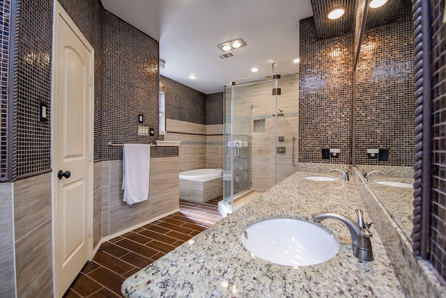 full bathroom featuring a garden tub, a sink, a stall shower, and tile walls