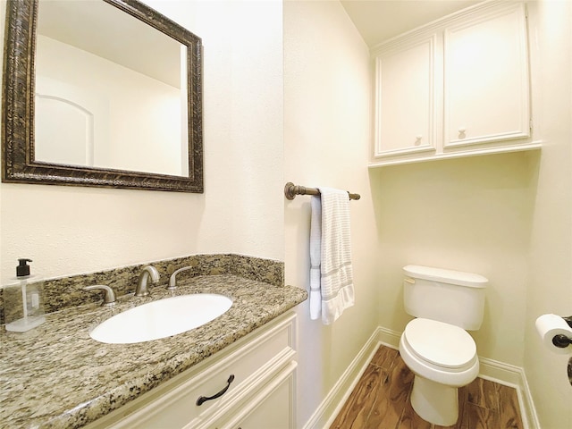 bathroom with baseboards, vanity, toilet, and wood finished floors