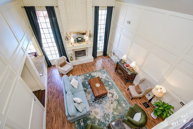 living room with a fireplace, a healthy amount of sunlight, wood finished floors, and a decorative wall
