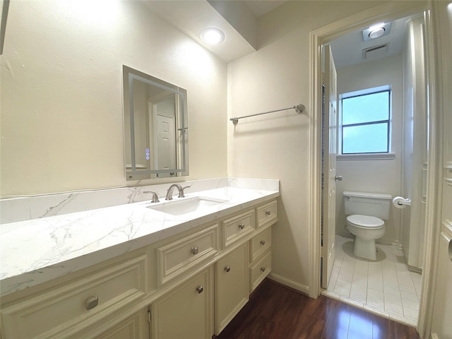 bathroom featuring toilet, visible vents, wood finished floors, and vanity