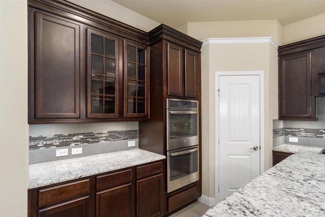 kitchen featuring double oven, dark brown cabinets, and glass insert cabinets