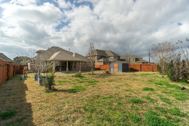 view of yard with a fenced backyard, a patio area, a shed, and an outbuilding