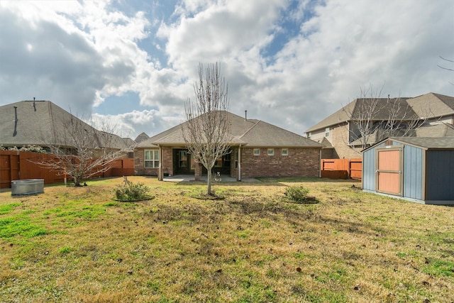 back of property with an outdoor structure, a patio, a fenced backyard, brick siding, and a storage shed