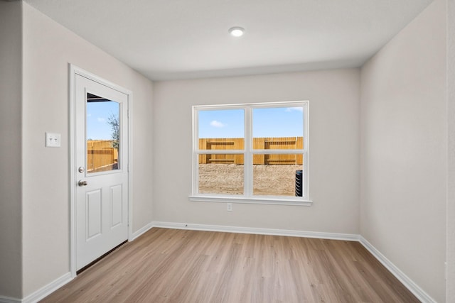 doorway featuring baseboards, plenty of natural light, and light wood finished floors