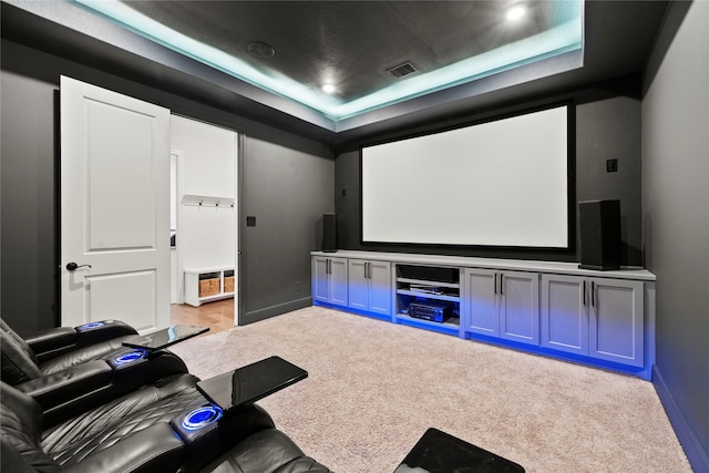 carpeted home theater room with visible vents, a raised ceiling, and baseboards