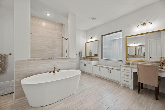 full bathroom featuring visible vents, vanity, tile walls, tiled shower, and a soaking tub