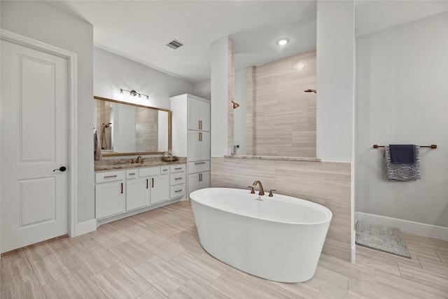 full bathroom featuring visible vents, tile walls, vanity, a soaking tub, and tiled shower