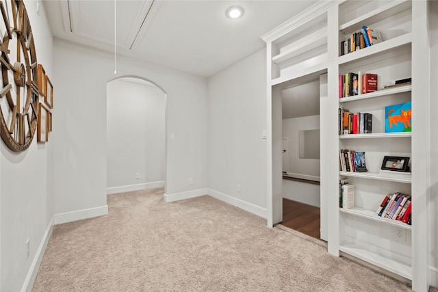 carpeted empty room with arched walkways, baseboards, and attic access