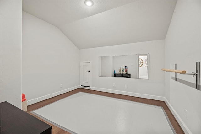 interior space featuring baseboards, vaulted ceiling, and dark wood-type flooring