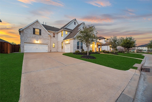 view of front of property with concrete driveway, an attached garage, fence, and a yard