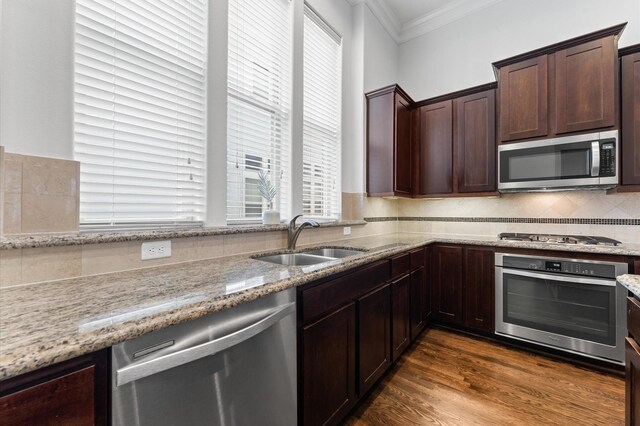 kitchen featuring appliances with stainless steel finishes, ornamental molding, a sink, and plenty of natural light