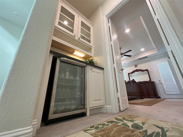 bar featuring beverage cooler, a ceiling fan, a textured wall, and carpet floors