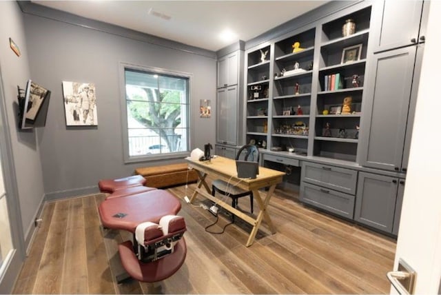 office featuring baseboards, built in desk, and light wood finished floors