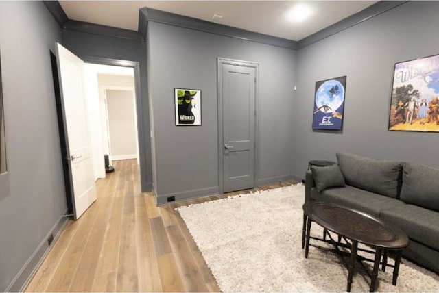living room with crown molding, baseboards, and light wood-style flooring