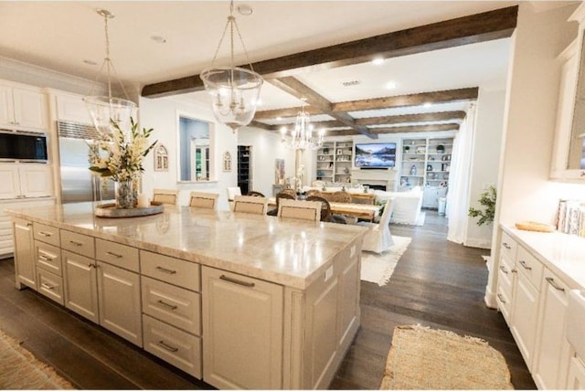 kitchen featuring appliances with stainless steel finishes, an inviting chandelier, beam ceiling, open floor plan, and dark wood-type flooring