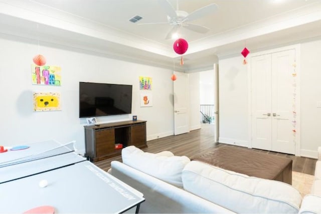 living area featuring baseboards, ornamental molding, ceiling fan, and wood finished floors