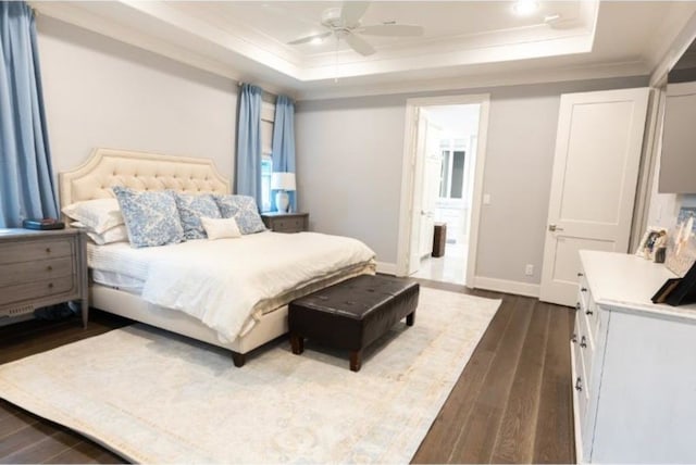 bedroom featuring crown molding, baseboards, a tray ceiling, and dark wood-type flooring
