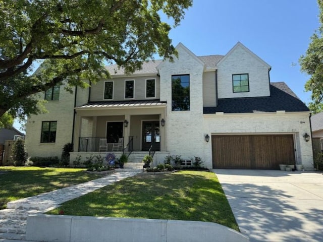 view of front of property with a front lawn, covered porch, stone siding, a standing seam roof, and concrete driveway
