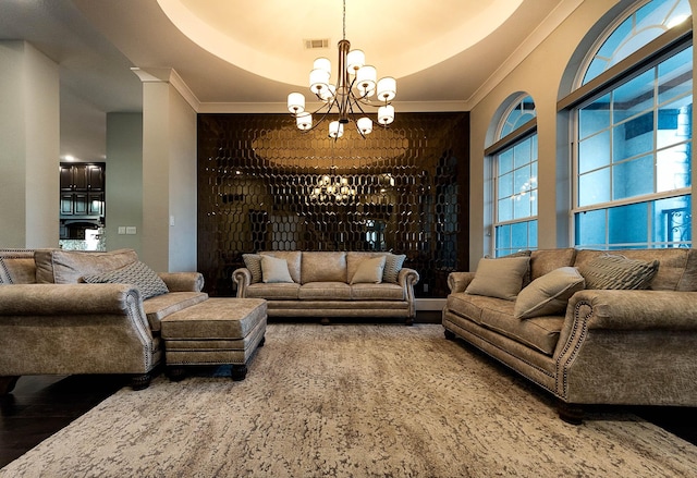 living room featuring crown molding, a chandelier, wood finished floors, and visible vents