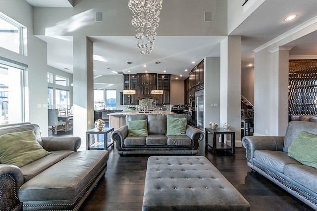 living area with dark wood-style flooring, a chandelier, recessed lighting, and a towering ceiling