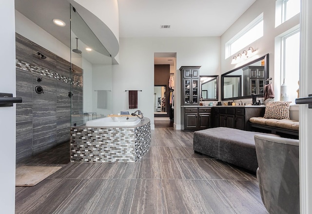 full bathroom featuring a walk in shower, a high ceiling, vanity, visible vents, and a bath