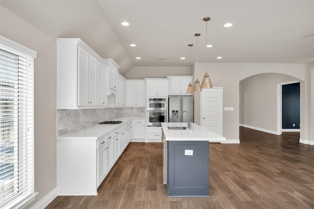 8106 Triumph Bend Way, Magnolia, TX 77354 - kitchen featuring decorative backsplash, appliances with stainless steel finishes, arched walkways, white cabinetry, and dark wood-type flooring