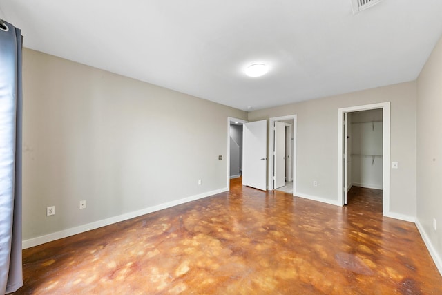 unfurnished bedroom with a walk in closet, visible vents, baseboards, a closet, and concrete floors