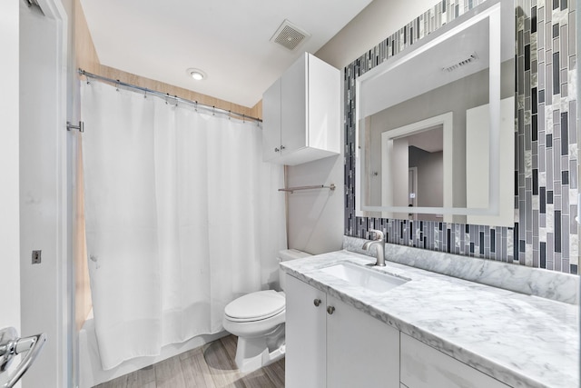 bathroom featuring visible vents, vanity, wood finished floors, toilet, and shower / tub combo