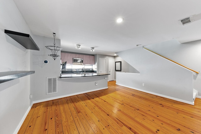 kitchen with baseboards, stainless steel microwave, a peninsula, and visible vents