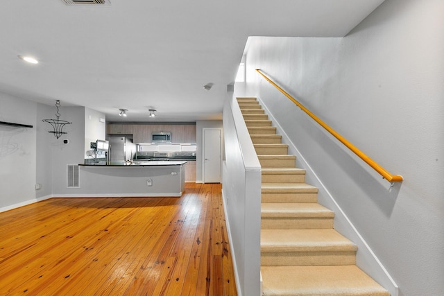 staircase with recessed lighting, baseboards, visible vents, and hardwood / wood-style flooring