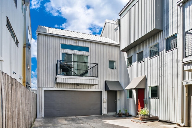 view of front of house featuring concrete driveway, a garage, fence, and metal roof